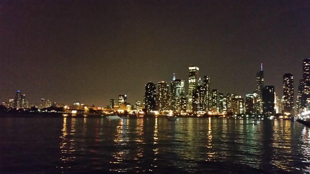 Chicago skyline lit up at night, reflected in Lake Michigan