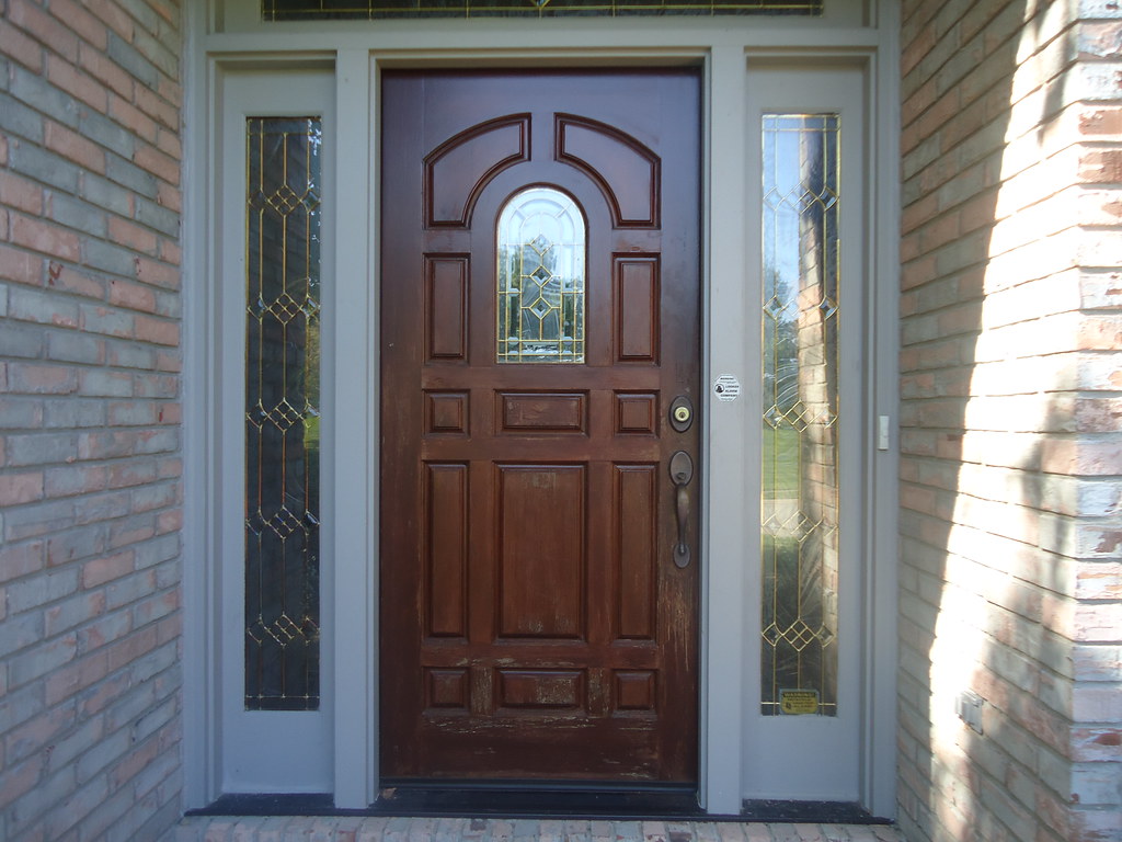 Wooden front door with glass side panels set in a brick entryway